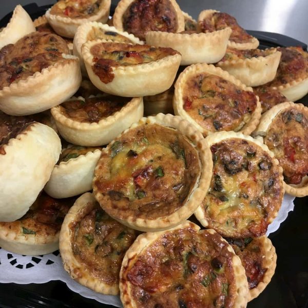 A plate piled high with mixed mini-quiches.