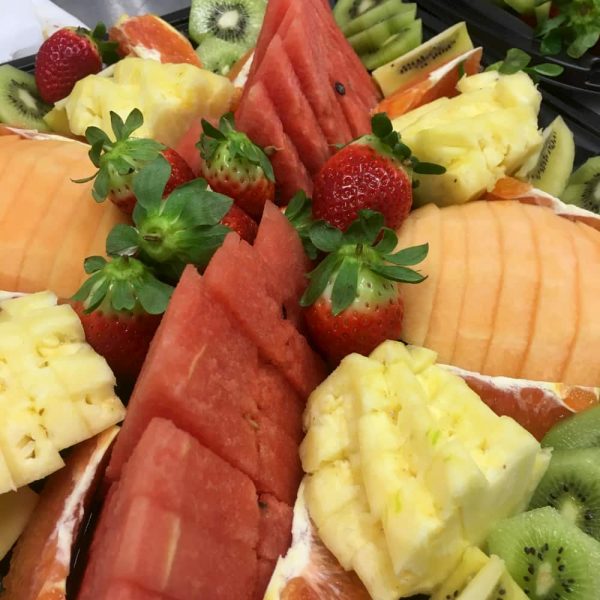 A platter of sliced water mellon, rock mellon, pineapple and strawberries.