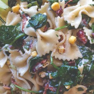 A mix of ribbon pasta, baby spinach, corn and bacon.