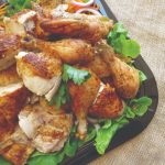 A platter of roasted pieces of chicken on a bed of fresh lettuce.
