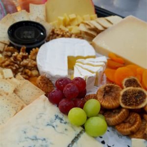 A plate of mixed cheeses with dried figs and grapes.