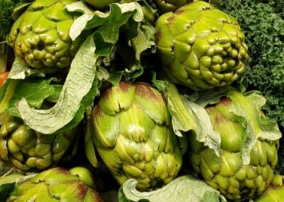 Fresh green artichokes stacked up on a shelf.