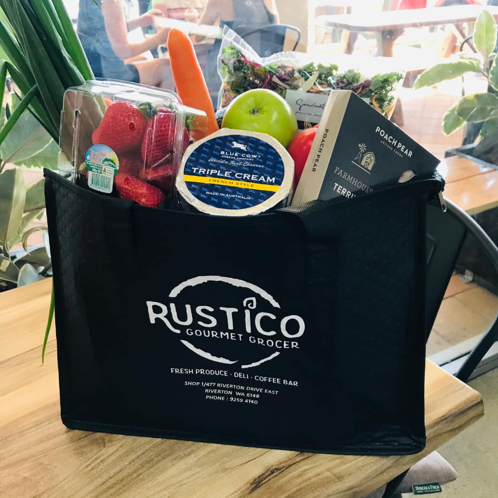A Rustico shopping bag filled with groceries including cheese and vegetables. 