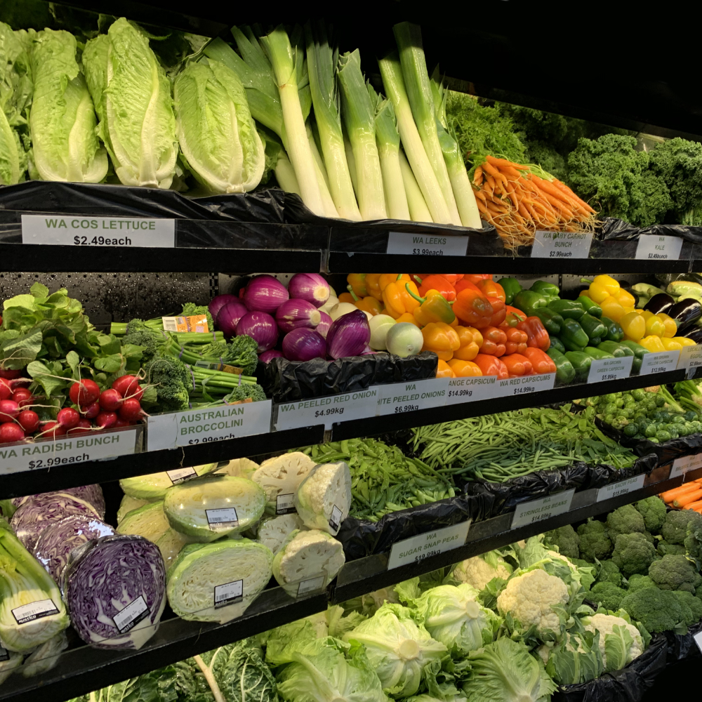 Shelves full of vegetables including leeks and lettuce and green beans. 